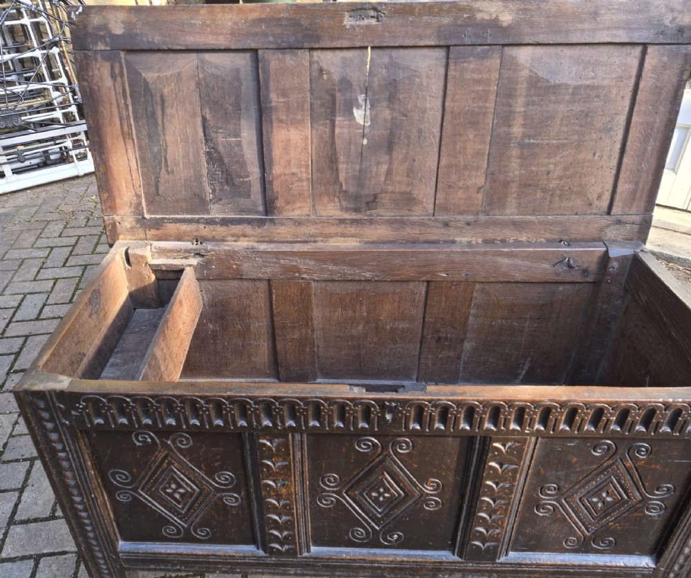 A dark carved oak coffer featuring a three-panel front with carved diamond lozenge patterns and an arcaded top rail. View III