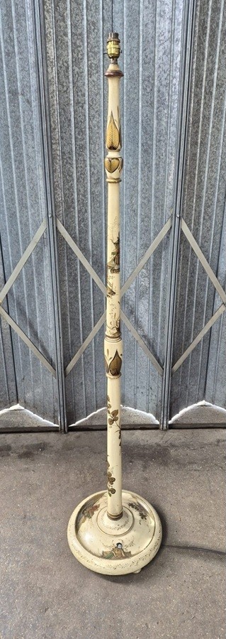 An Edwardian chinoiserie standard lamp with a cream painted turned column shaft featuring hand-painted gold oriental figures and landscapes, ending in a circular base.