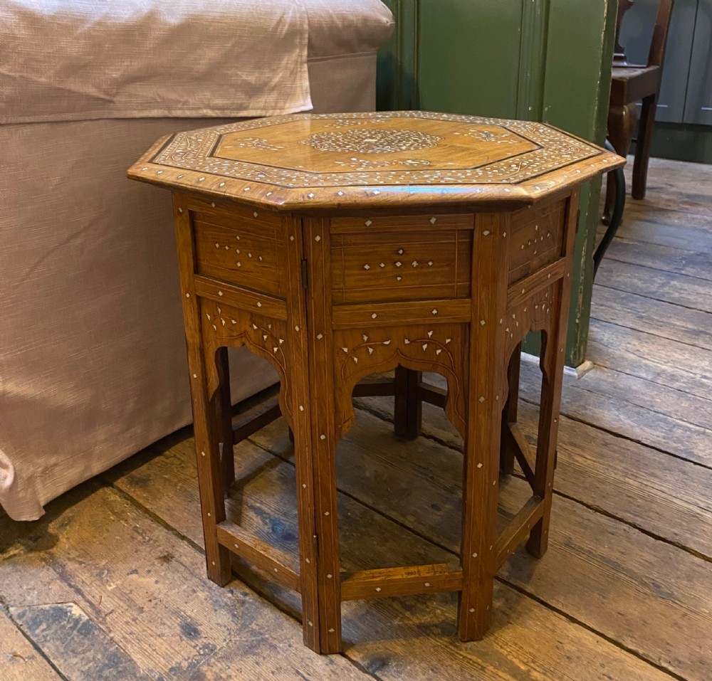 A 19th-century octagonal warm brown wood side table featuring Moorish arch carved legs and geometric mother-of-pearl inlay across the top and aprons.