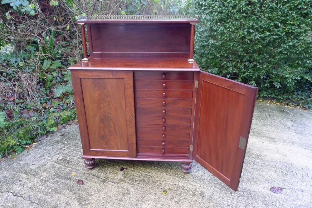 Victorian flame mahogany collectors cabinet featuring an upper shelf with a brass gallery and double doors opening to reveal multiple shallow drawers. View V