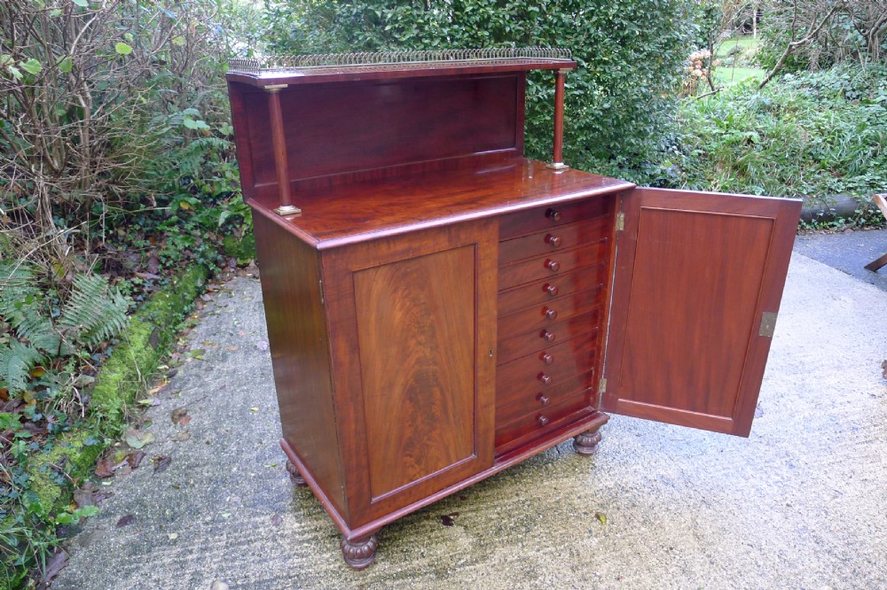 Victorian flame mahogany collectors cabinet featuring an upper shelf with a brass gallery and double doors opening to reveal multiple shallow drawers. View VI