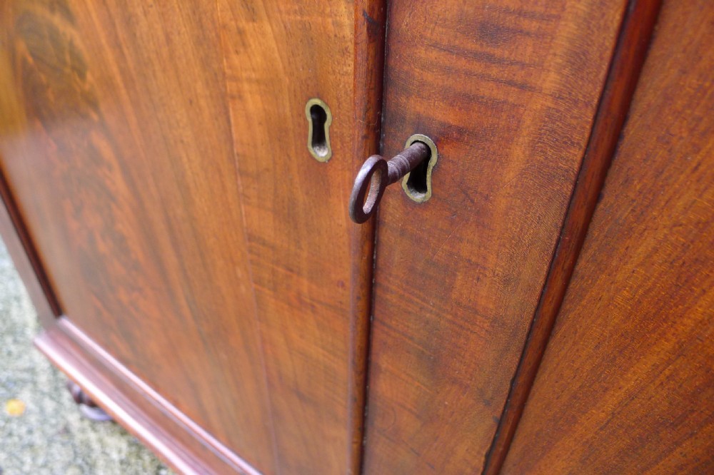 Victorian flame mahogany collectors cabinet featuring an upper shelf with a brass gallery and double doors opening to reveal multiple shallow drawers. View X
