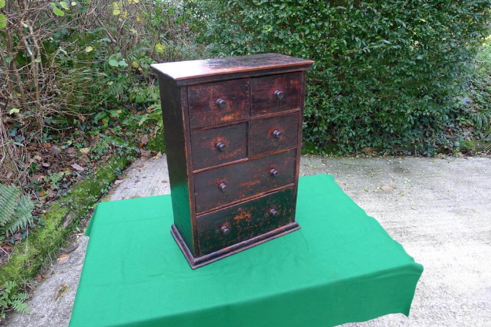 A small dark-stained deal wood collectors cabinet featuring six drawers with turned wooden knobs. View II