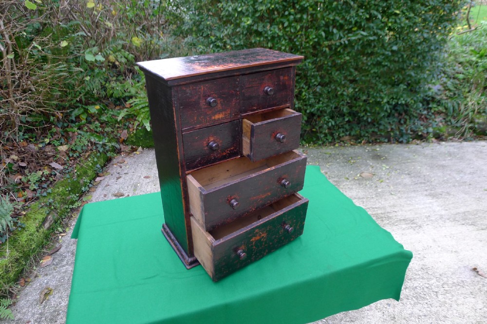 A small dark-stained deal wood collectors cabinet featuring six drawers with turned wooden knobs. View IV