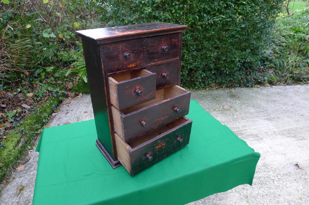 A small dark-stained deal wood collectors cabinet featuring six drawers with turned wooden knobs. View V