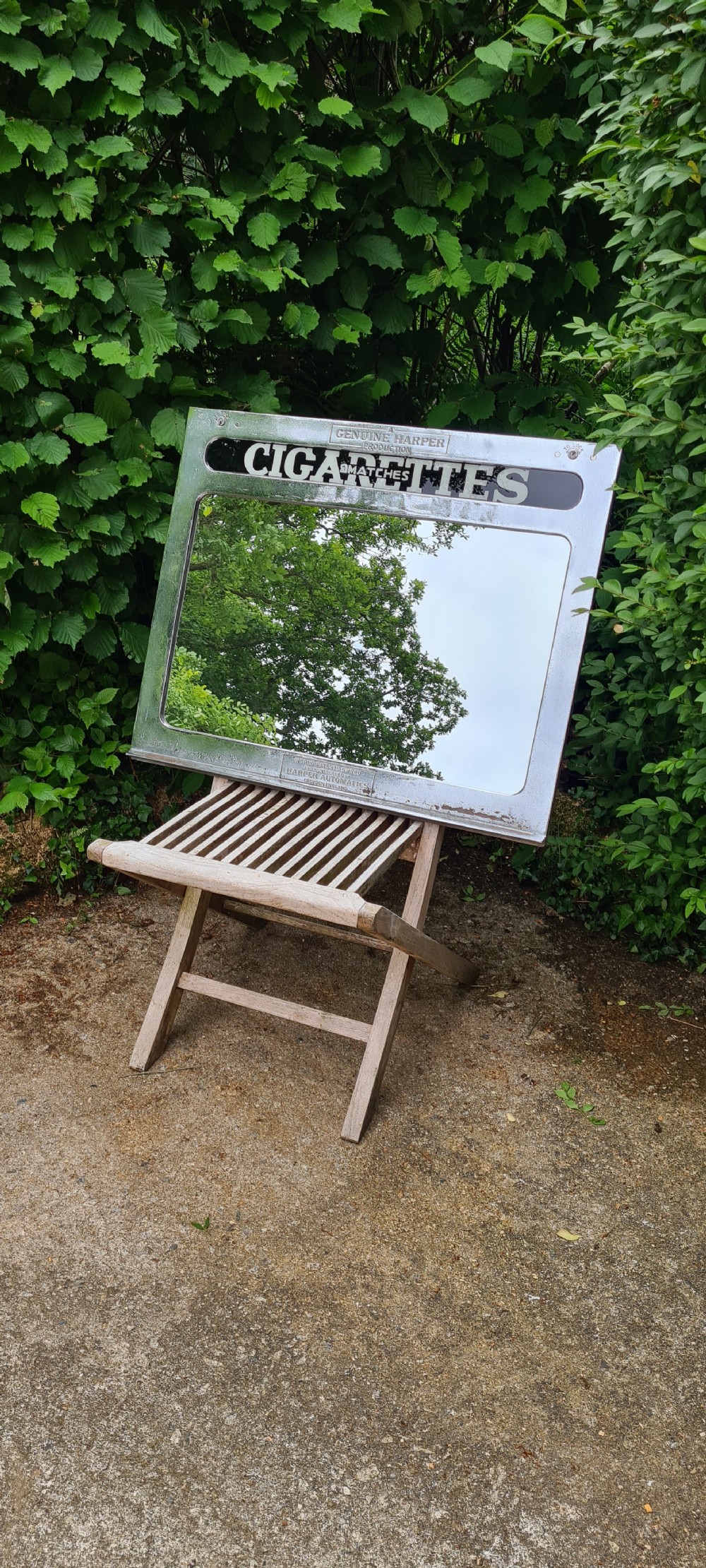 A rectangular 1930s chrome advertising mirror with black lettered signage for cigarettes and matches by Harper Automatics.