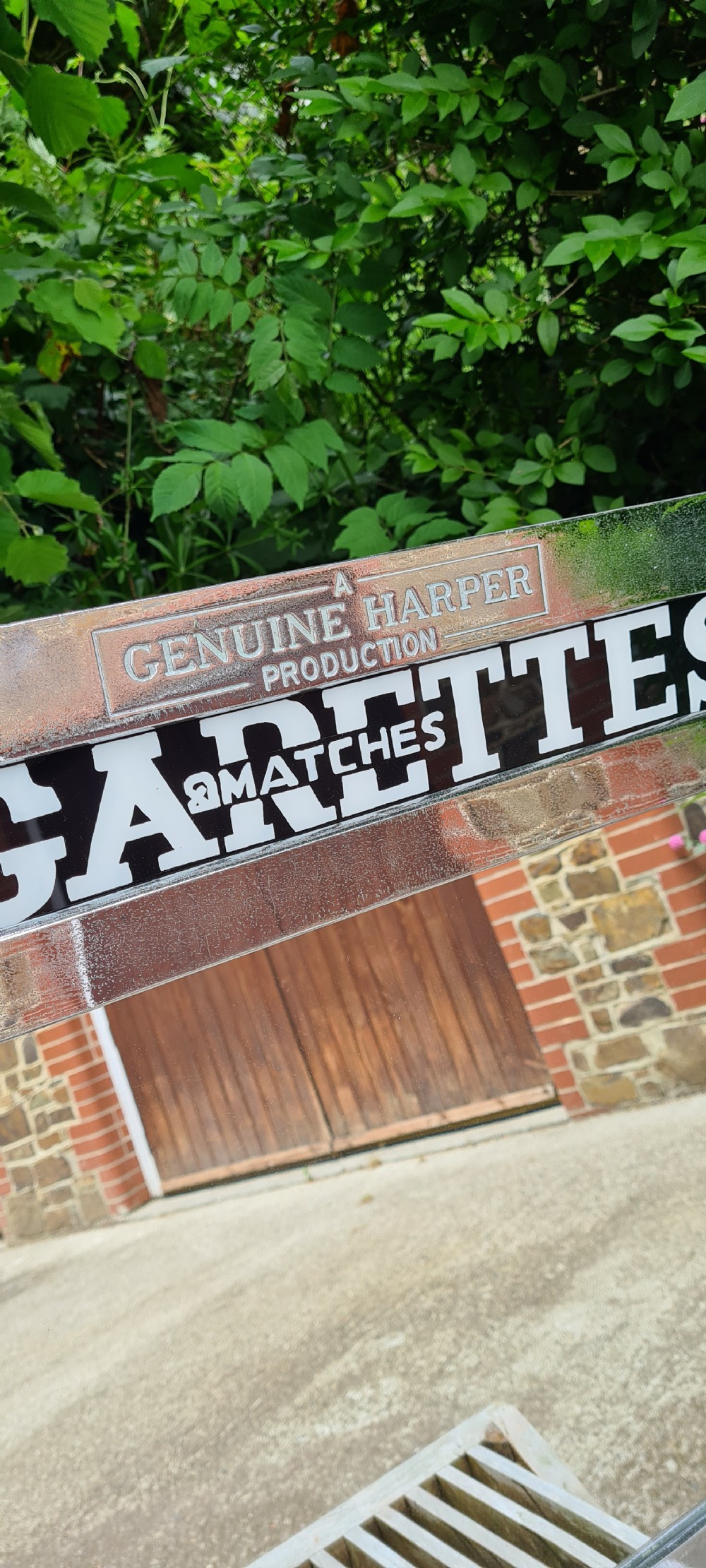 A rectangular 1930s chrome advertising mirror with black lettered signage for cigarettes and matches by Harper Automatics. View VI