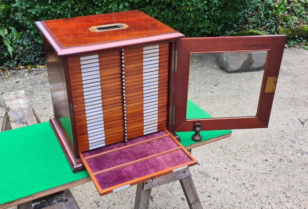 A Victorian mahogany tabletop microscope slide cabinet with a glass front door, numbered shallow drawers, and an inset brass carrying handle on top. View IX