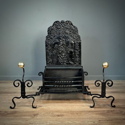 fig 2. A black cast and wrought iron fire basket featuring a relief-decorated fireback, slatted log holder, scrolled iron side supports, and polished brass ball finials.
