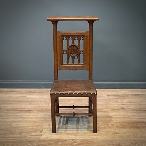 fig 2. A carved oak Gothic Revival chair featuring a traceried back panel, leather studded seat, and turned stretchers.