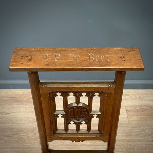 fig 3. A carved oak Gothic Revival chair featuring a traceried back panel, leather studded seat, and turned stretchers.