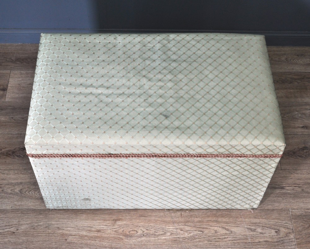 A rectangular Victorian blanket box upholstered in cream lattice-patterned fabric featuring terracotta braid trim around the lid edge. View IX