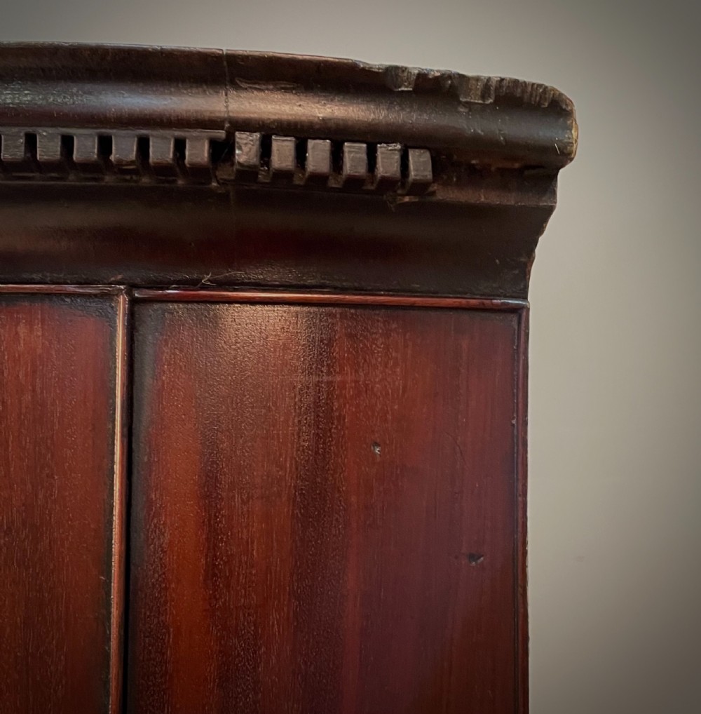 A Georgian mahogany bow-front hanging corner cabinet featuring double doors with flame timber grain, brass escutcheon, and a dentil-moulded top cornice. View III
