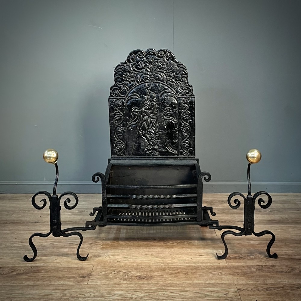 A black cast and wrought iron fire basket featuring a relief-decorated fireback, slatted log holder, scrolled iron side supports, and polished brass ball finials. View III
