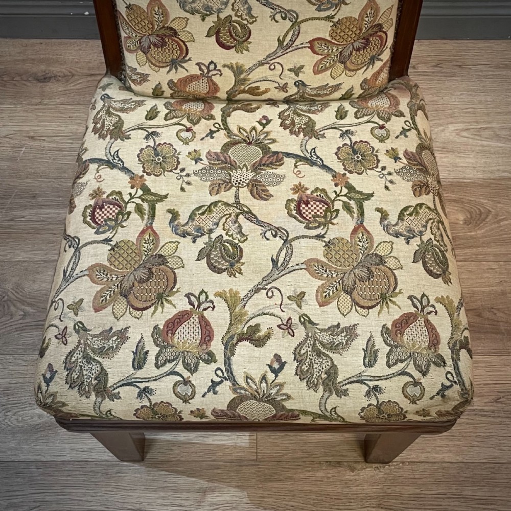 An antique walnut nursing chair featuring a tall rectangular backrest, floral upholstery, stud trim, and tapered wooden legs. View IV