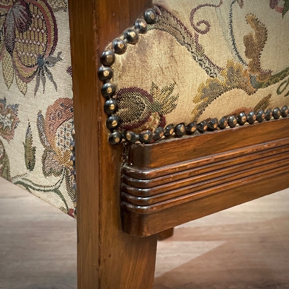 An antique walnut nursing chair featuring a tall rectangular backrest, floral upholstery, stud trim, and tapered wooden legs. View VII