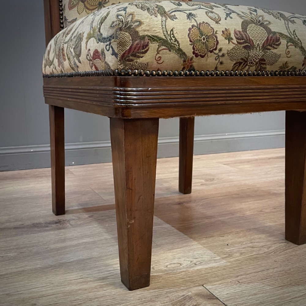 An antique walnut nursing chair featuring a tall rectangular backrest, floral upholstery, stud trim, and tapered wooden legs. View VIII