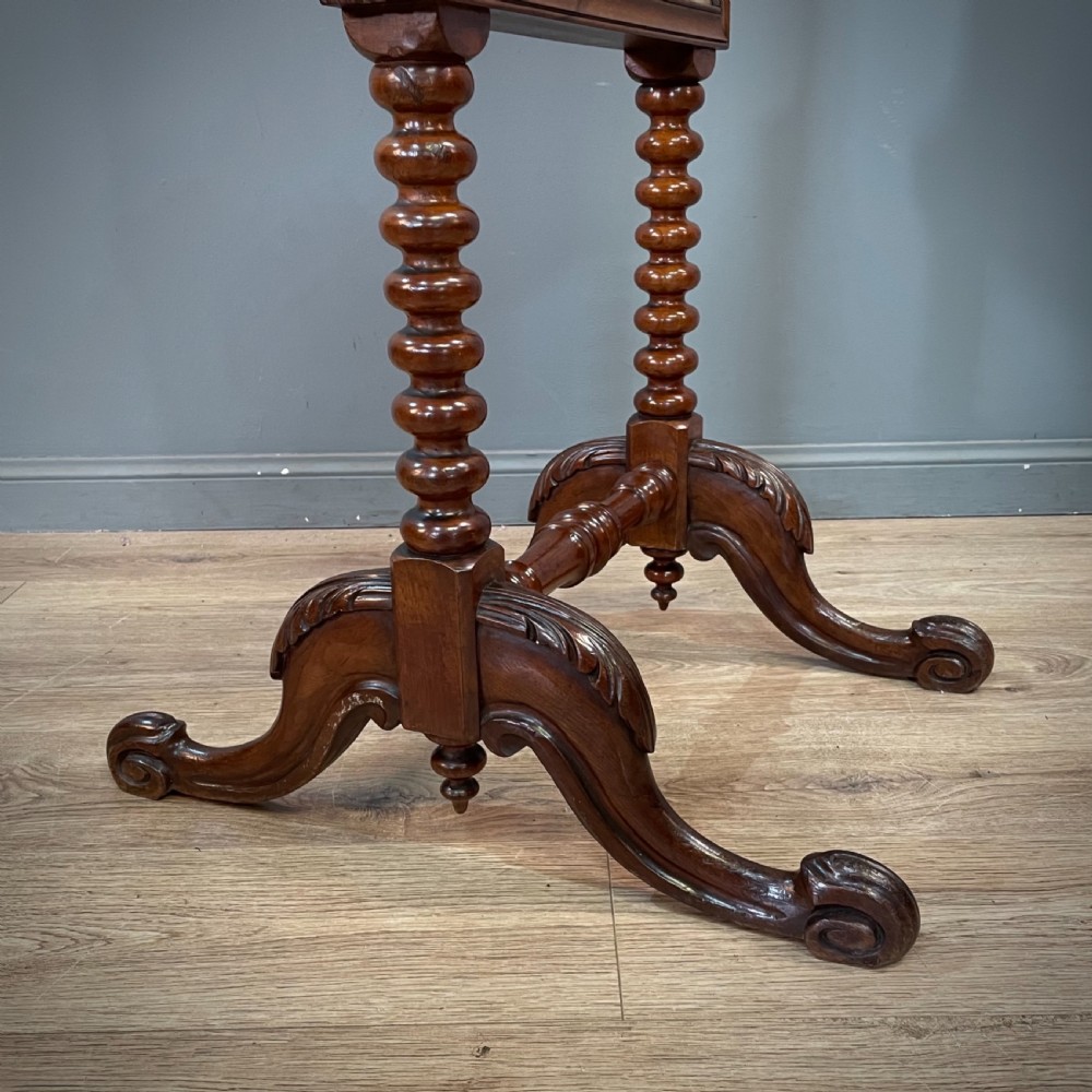 A Victorian mahogany fire screen featuring bobbin-turned uprights, carved feet, and a framed needlework panel displaying a floral bouquet. View V