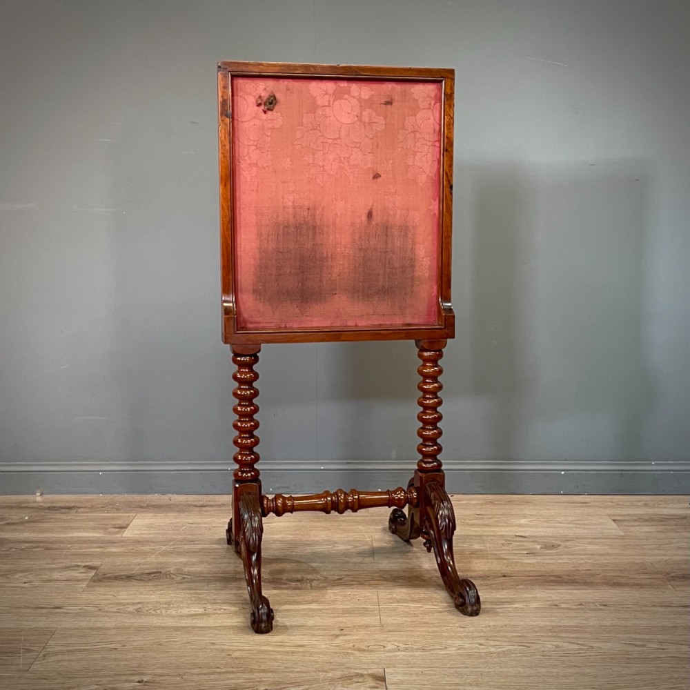 A Victorian mahogany fire screen featuring bobbin-turned uprights, carved feet, and a framed needlework panel displaying a floral bouquet. View VII