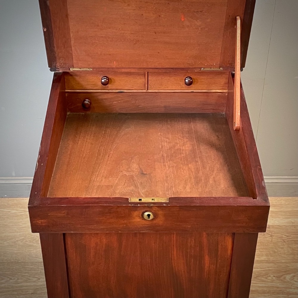 A William IV mahogany Davenport desk featuring a sloped leather writing slope, turned spindle gallery top, side drawers, and brass castors. View IV