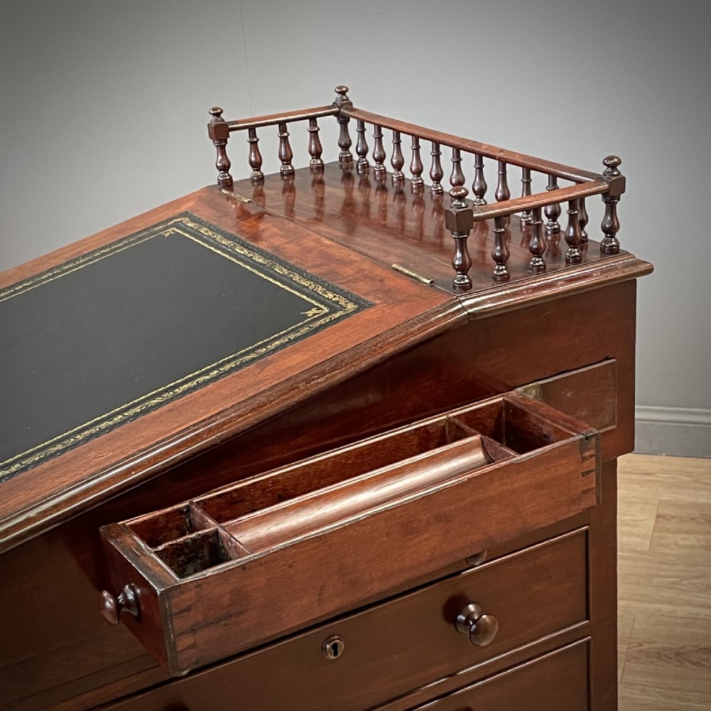 A William IV mahogany Davenport desk featuring a sloped leather writing slope, turned spindle gallery top, side drawers, and brass castors. View XV