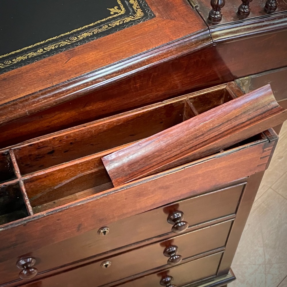 A William IV mahogany Davenport desk featuring a sloped leather writing slope, turned spindle gallery top, side drawers, and brass castors. View XVII