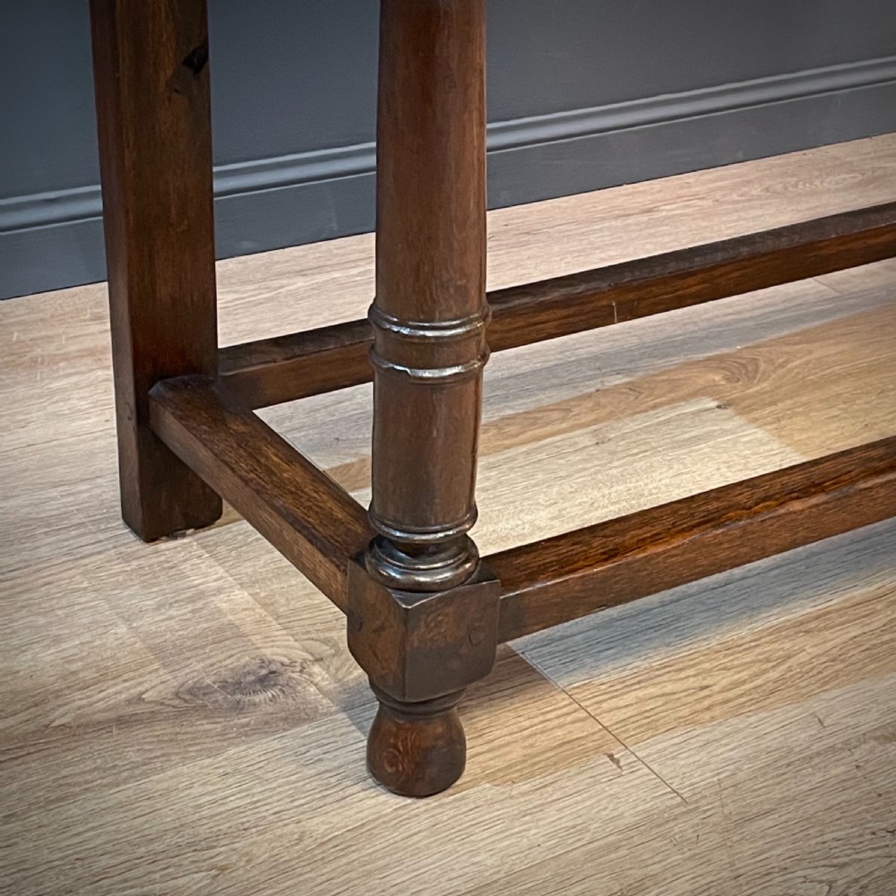 An antique dark oak livery cupboard featuring a carved pierced ventilation panel, central arch motif, turned legs, and a lower stretcher base. View VIII