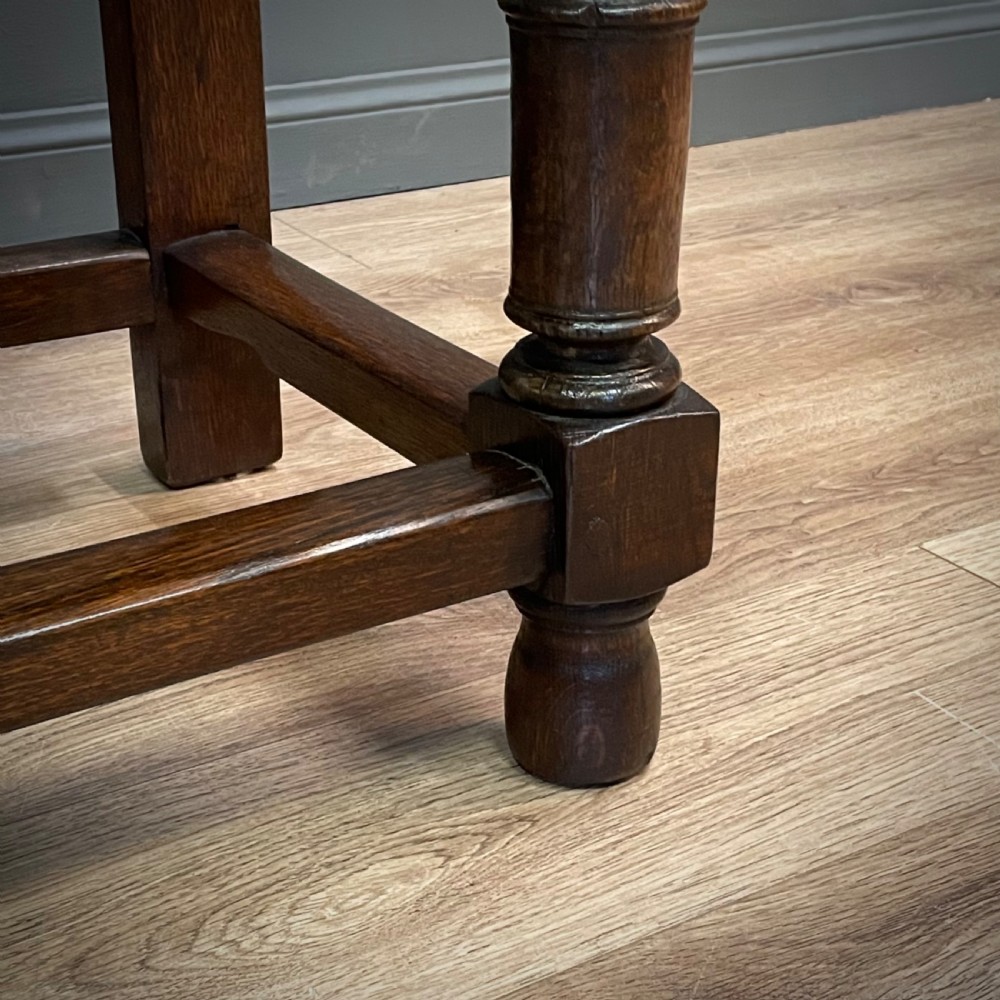 An antique dark oak livery cupboard featuring a carved pierced ventilation panel, central arch motif, turned legs, and a lower stretcher base. View XV