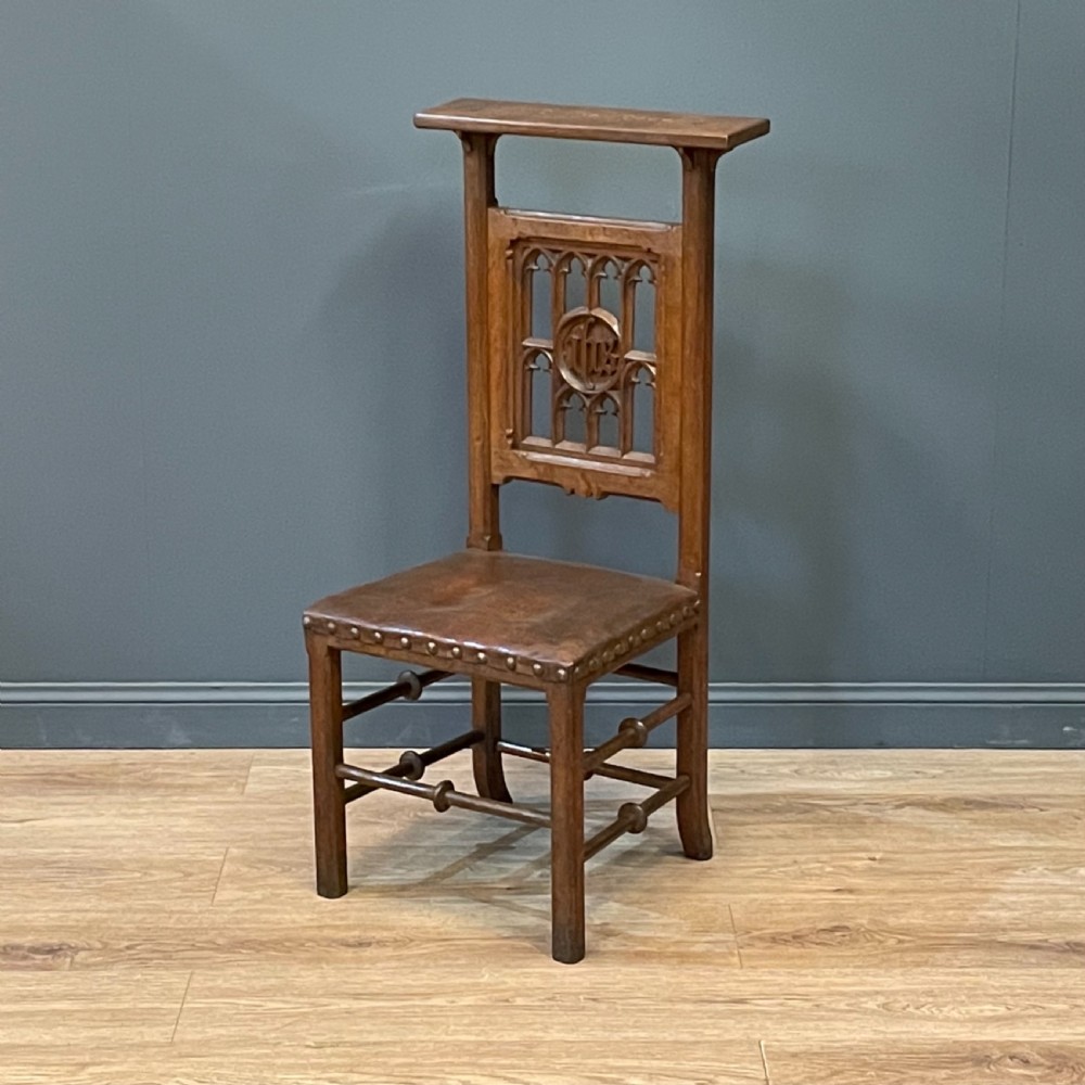 A carved oak Gothic Revival chair featuring a traceried back panel, leather studded seat, and turned stretchers. View II