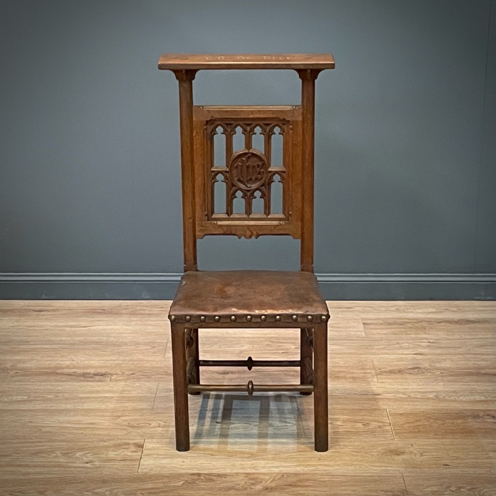 A carved oak Gothic Revival chair featuring a traceried back panel, leather studded seat, and turned stretchers. View III