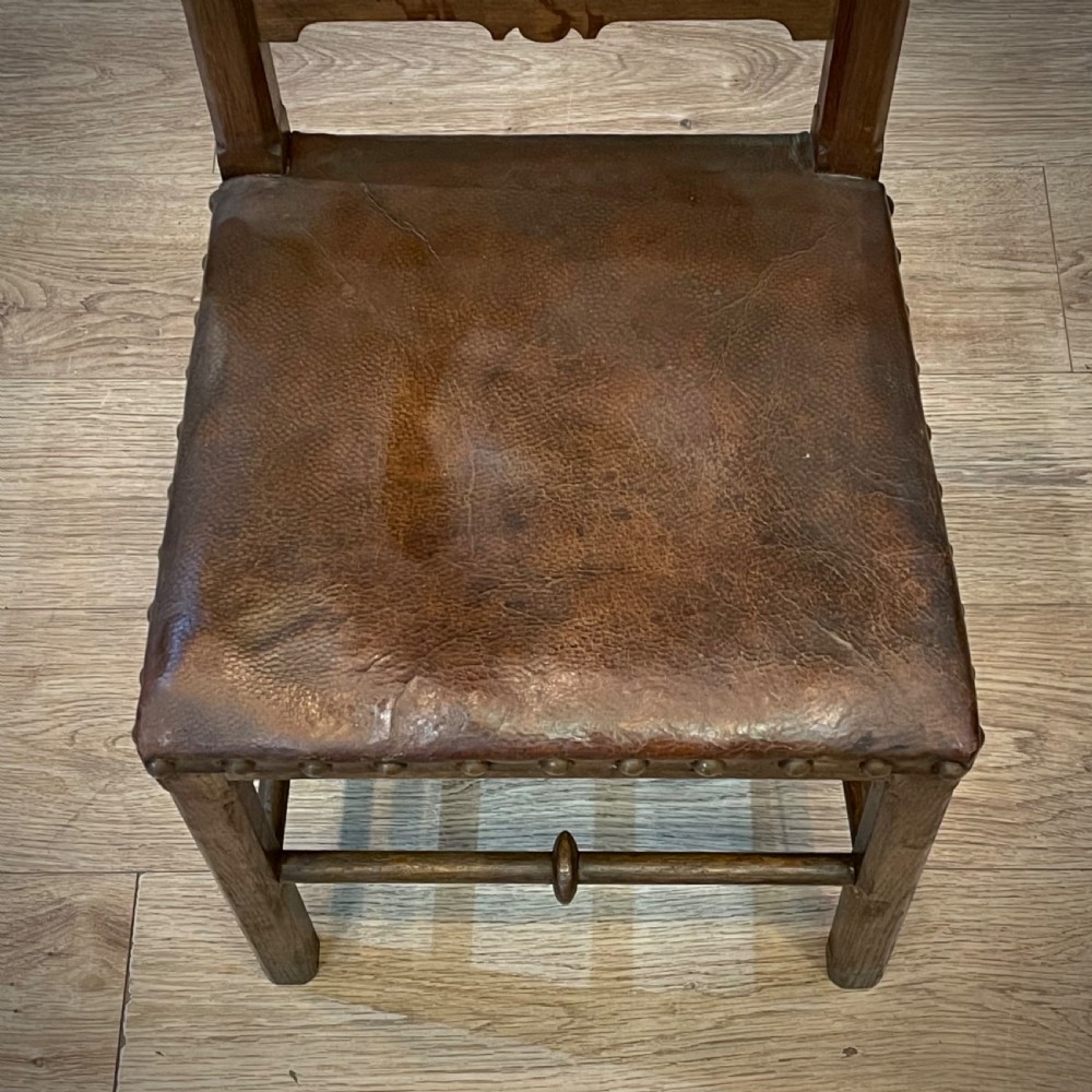 A carved oak Gothic Revival chair featuring a traceried back panel, leather studded seat, and turned stretchers. View VI