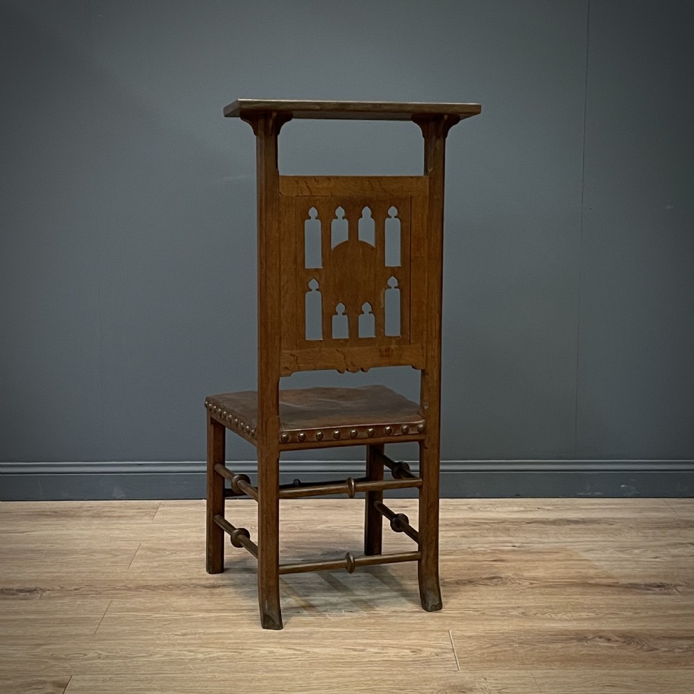A carved oak Gothic Revival chair featuring a traceried back panel, leather studded seat, and turned stretchers. View VIII