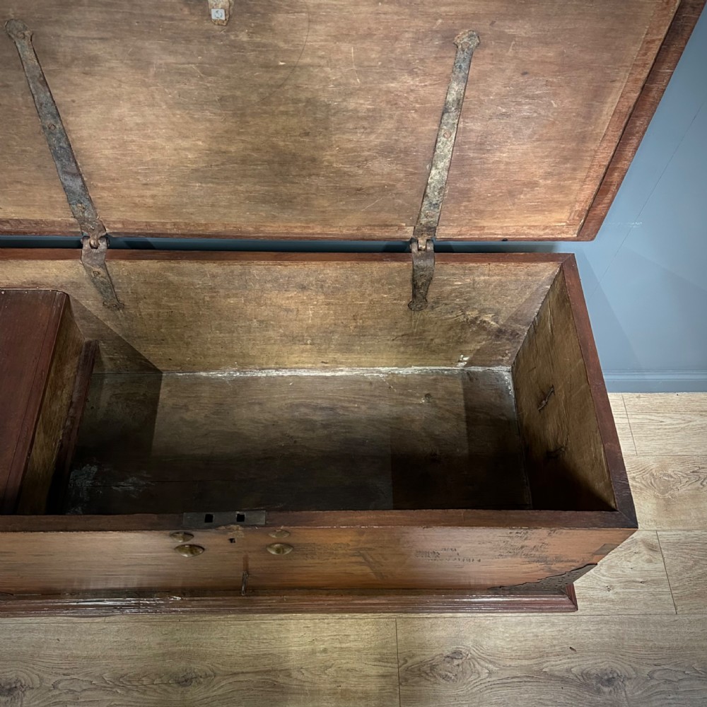A rustic warm brown teak marriage chest featuring iron latch hardware, brass corner brackets, and a raised wooden base supported by four solid wooden wheels. View IX