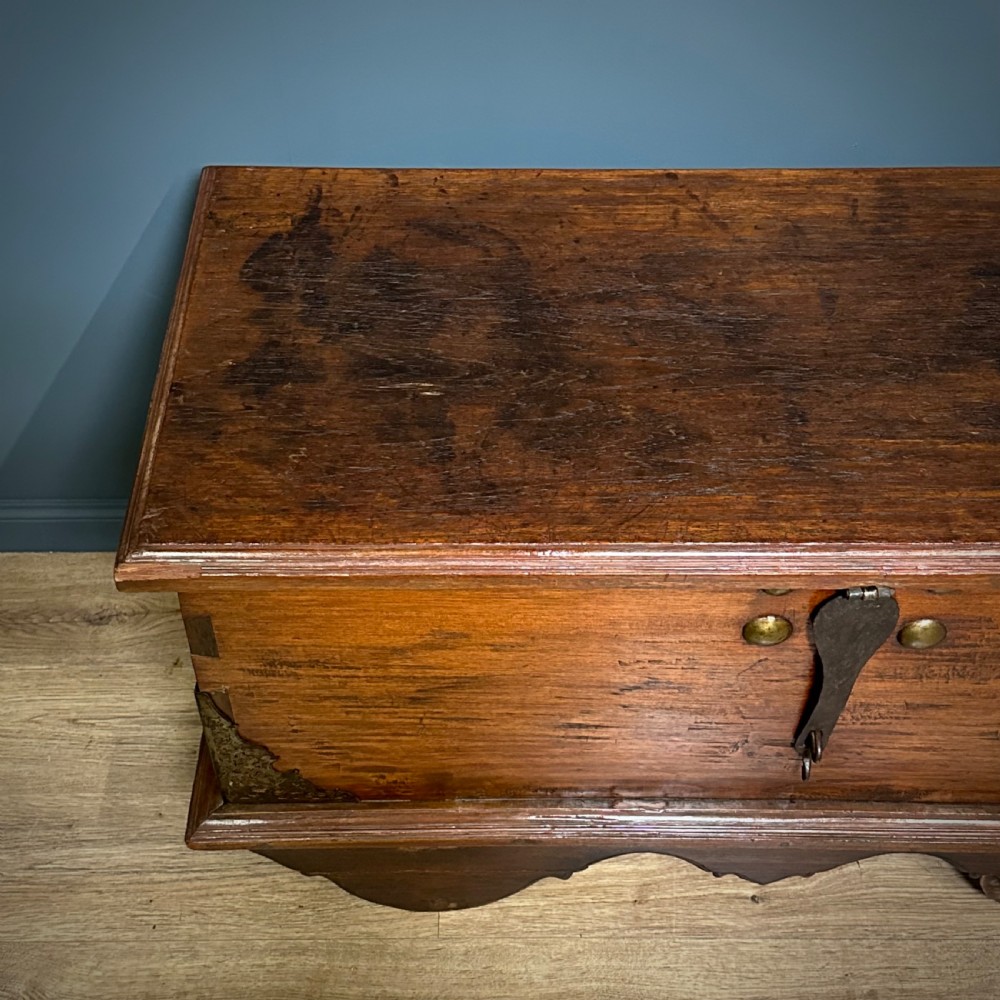 A rustic warm brown teak marriage chest featuring iron latch hardware, brass corner brackets, and a raised wooden base supported by four solid wooden wheels. View XIV