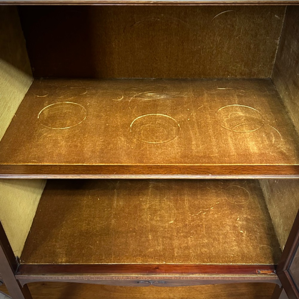 An Edwardian bow-fronted mahogany display cabinet featuring a central glazed door flanked by satinwood oval patera marquetry panels and an arched pediment. View VI