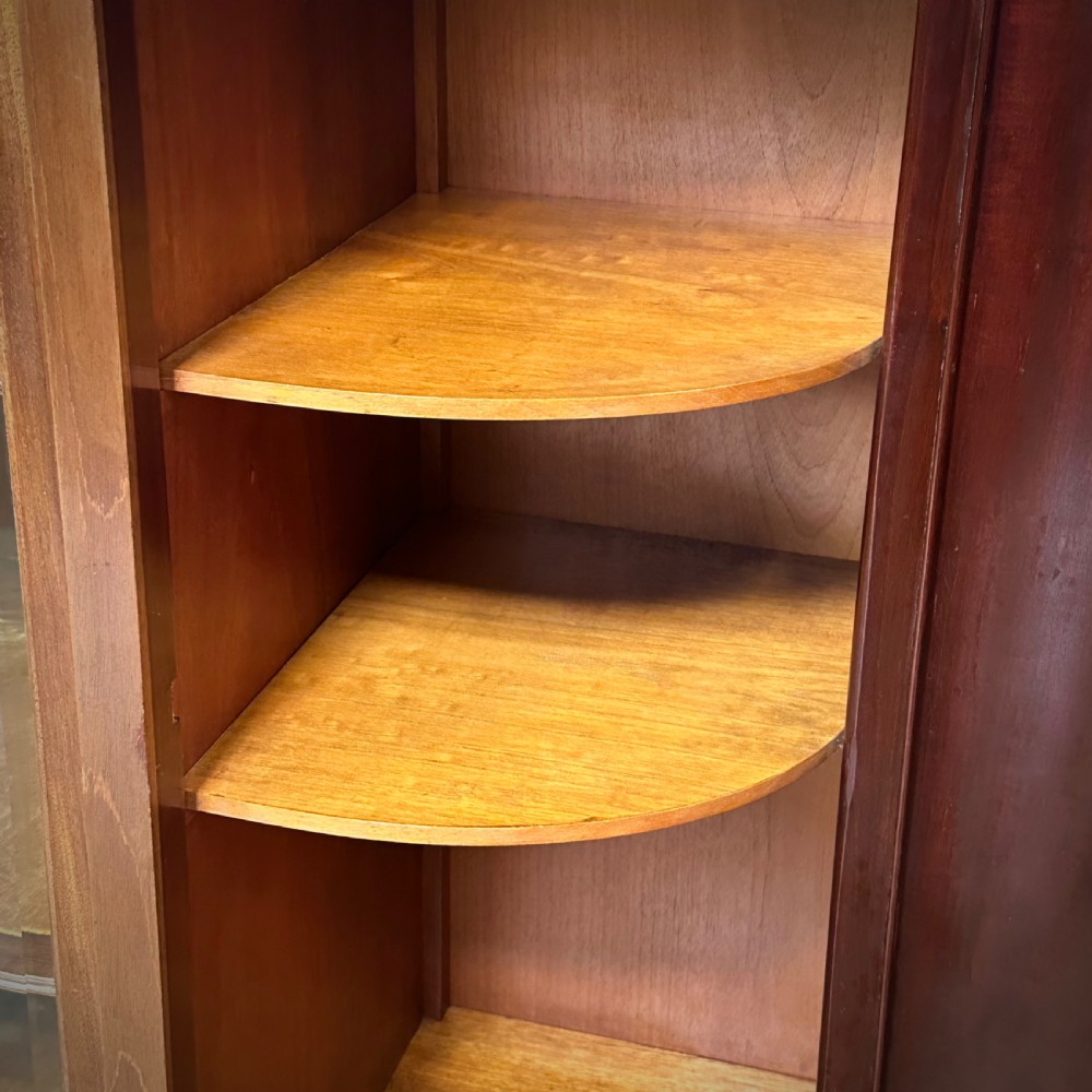 An Edwardian bow-fronted mahogany display cabinet featuring a central glazed door flanked by satinwood oval patera marquetry panels and an arched pediment. View X