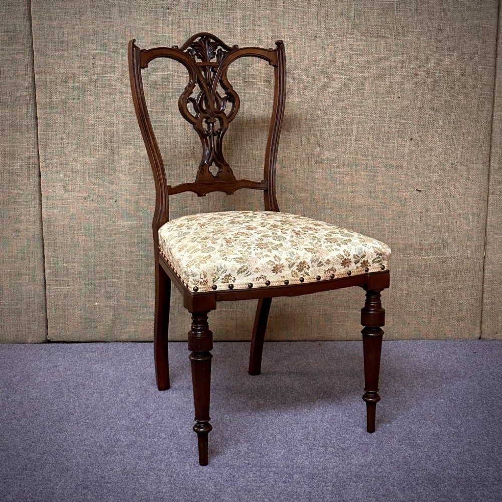 A set of four Edwardian mahogany dining chairs featuring pierced carved splats, patterned floral upholstered seats, and turned front legs. View II