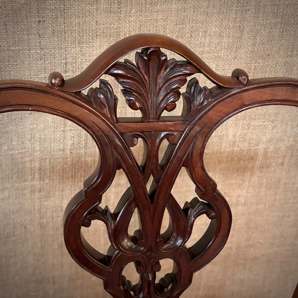 A set of four Edwardian mahogany dining chairs featuring pierced carved splats, patterned floral upholstered seats, and turned front legs. View V