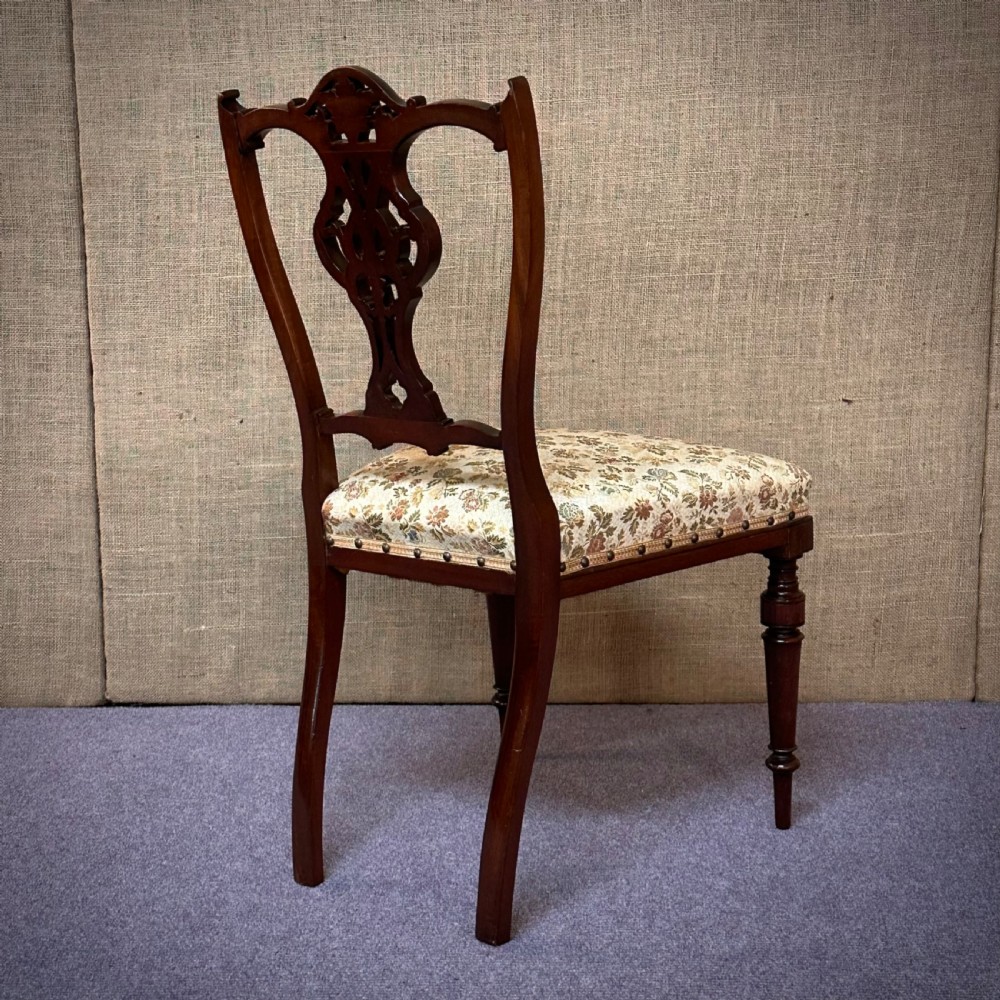 A set of four Edwardian mahogany dining chairs featuring pierced carved splats, patterned floral upholstered seats, and turned front legs. View VII