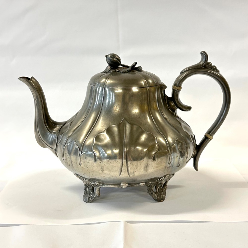 Victorian pewter teapot with a lobed body, curved spout, scrolled feet, and a bud-shaped lid finial.