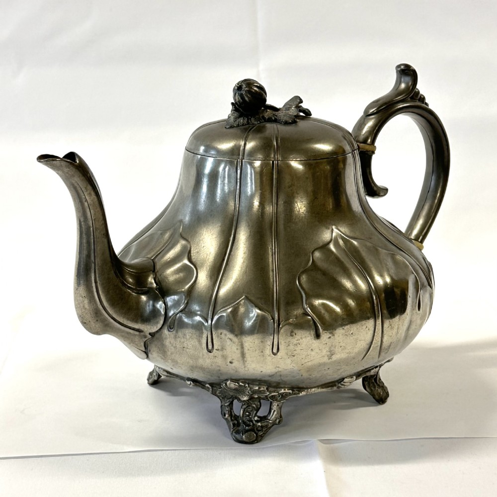 Victorian pewter teapot with a lobed body, curved spout, scrolled feet, and a bud-shaped lid finial. View IV