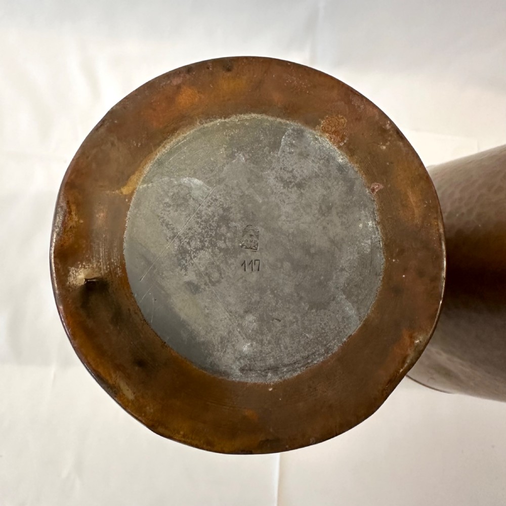 A pair of cylindrical brass vases featuring hand-hammered lower bodies and circular embossed floral medallions around the upper rim. View VII