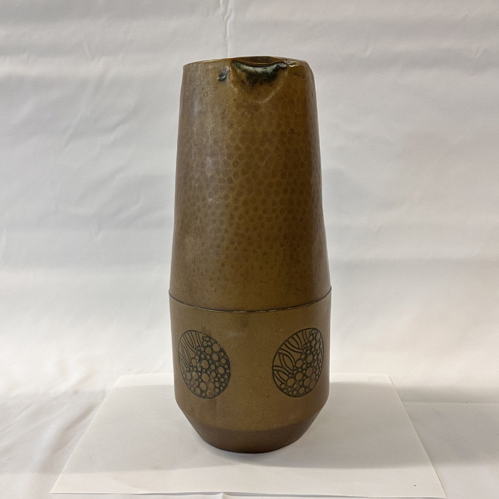 A pair of cylindrical brass vases featuring hand-hammered lower bodies and circular embossed floral medallions around the upper rim. View VIII