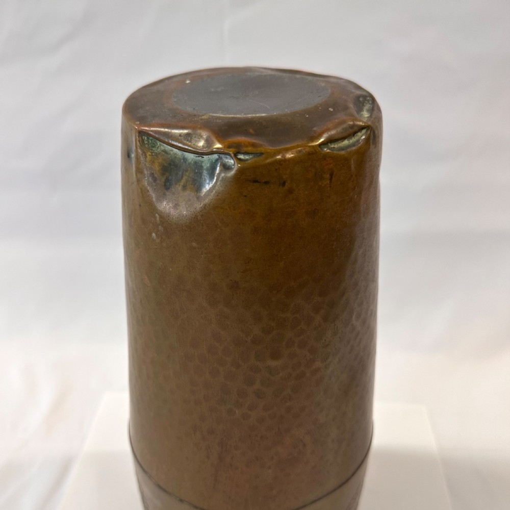 A pair of cylindrical brass vases featuring hand-hammered lower bodies and circular embossed floral medallions around the upper rim. View XII