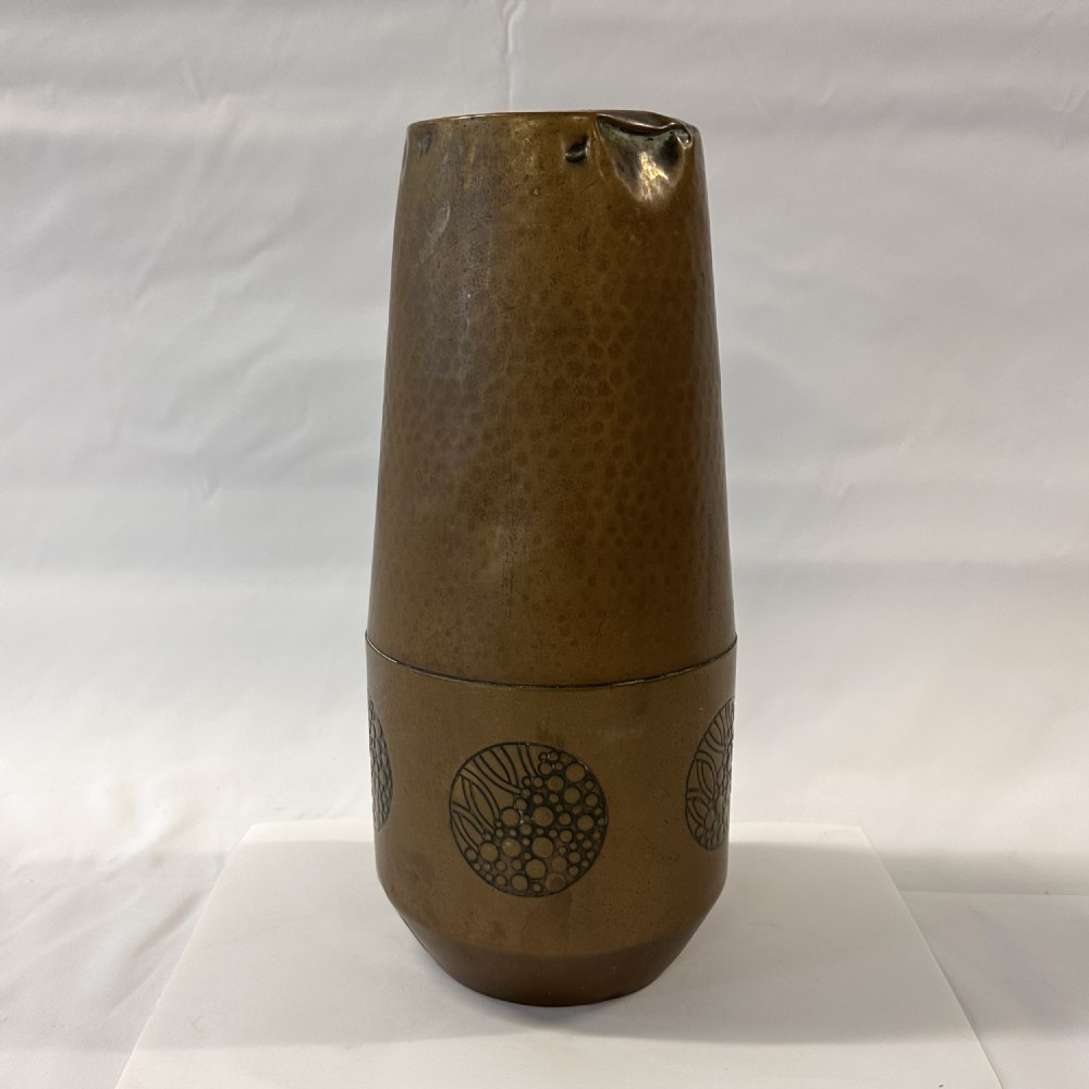 A pair of cylindrical brass vases featuring hand-hammered lower bodies and circular embossed floral medallions around the upper rim. View XIII