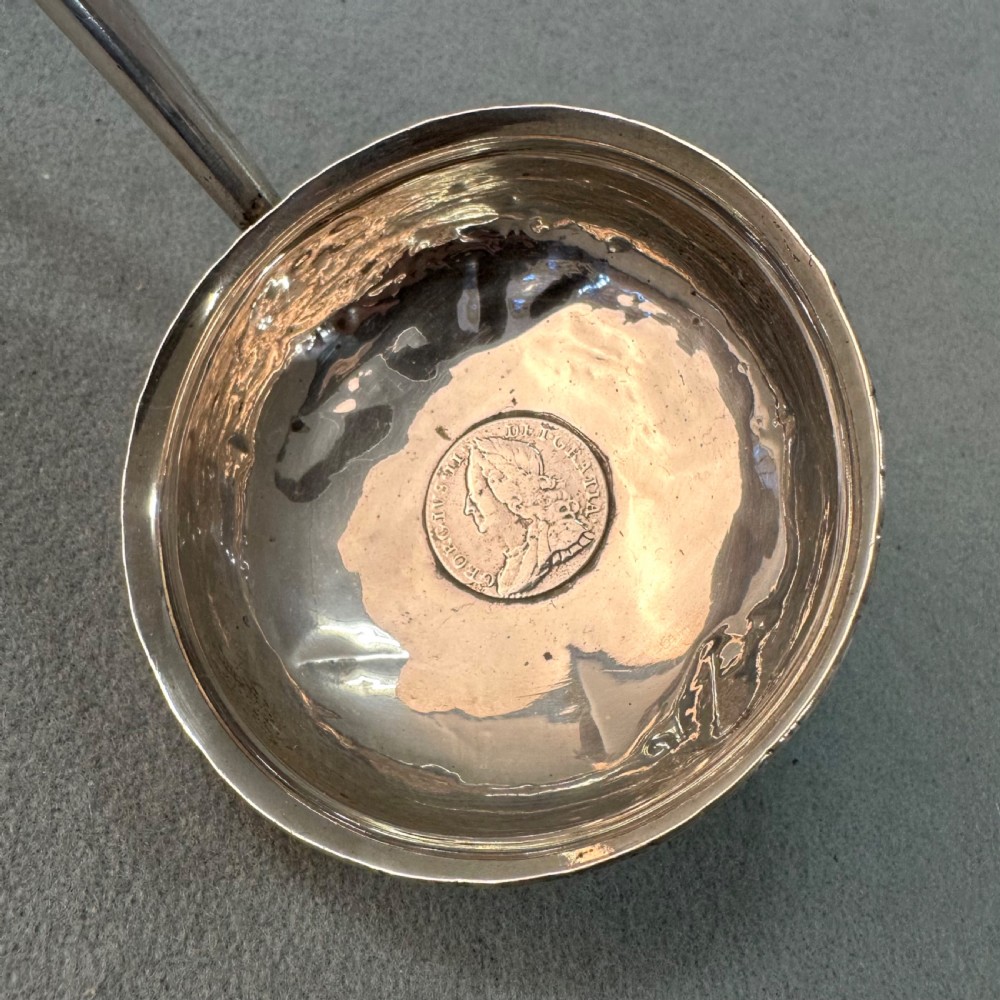 An 18th-century Georgian silver toddy ladle featuring an inset silver coin at the base of the bowl attached to a dark turned handle. View III