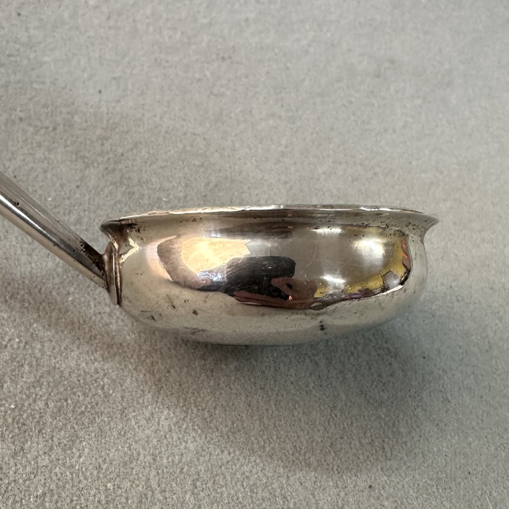 An 18th-century Georgian silver toddy ladle featuring an inset silver coin at the base of the bowl attached to a dark turned handle. View IV