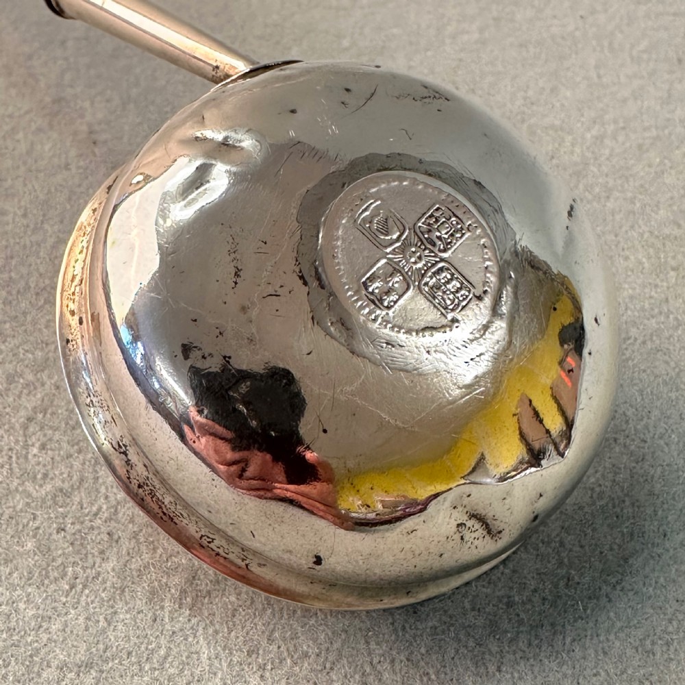 An 18th-century Georgian silver toddy ladle featuring an inset silver coin at the base of the bowl attached to a dark turned handle. View V