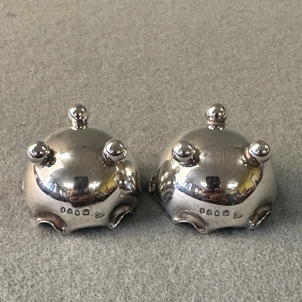 A pair of Victorian sterling silver open salt cellars featuring crimped rims, stamped hallmarks, and raised on three ball feet. View VII