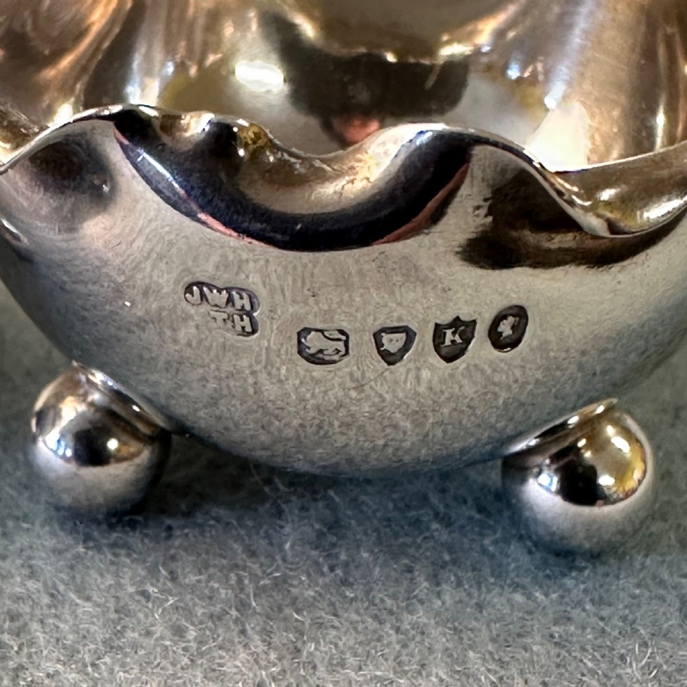 A pair of Victorian sterling silver open salt cellars featuring crimped rims, stamped hallmarks, and raised on three ball feet. View VIII